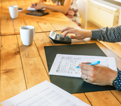 accountant using a calculator and filling in a document